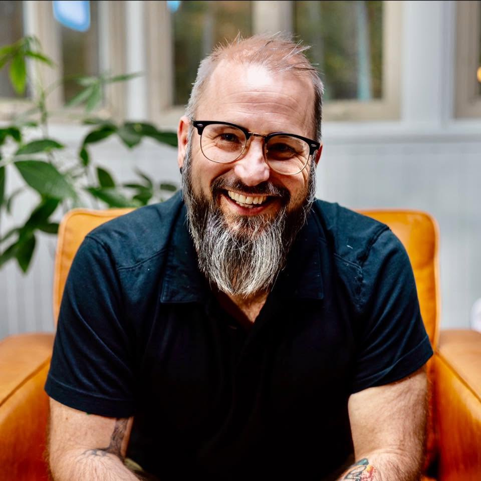 Dr. Andrew J. Bauman smiling in a chair